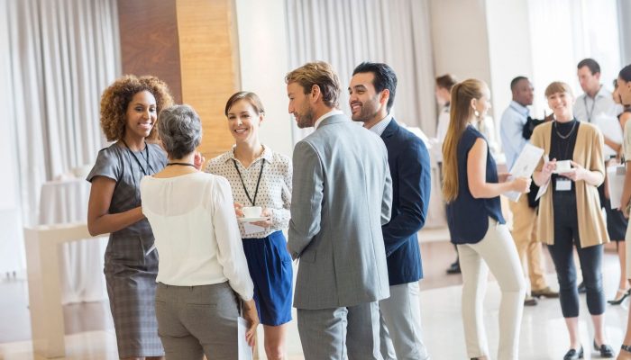 Group of business people standing in hall, smiling and talking together Group of business people standing in hall, smiling and talking together