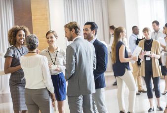 Group of business people standing in hall, smiling and talking together Group of business people standing in hall, smiling and talking together
